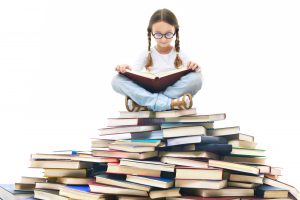 Portrait of cute girl with open book and looking at camera